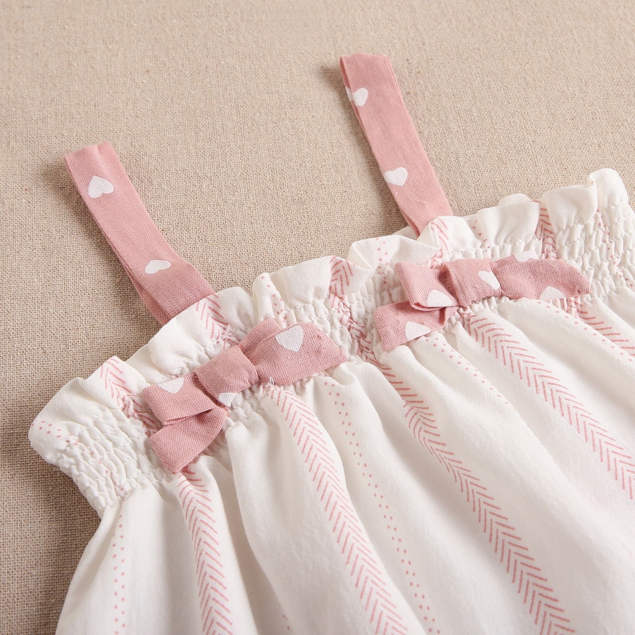 Imagen de Vestido de bebé niña con cubrepañal blanco con estampado en tonos rosas y combinado con rosa y corazones blancos