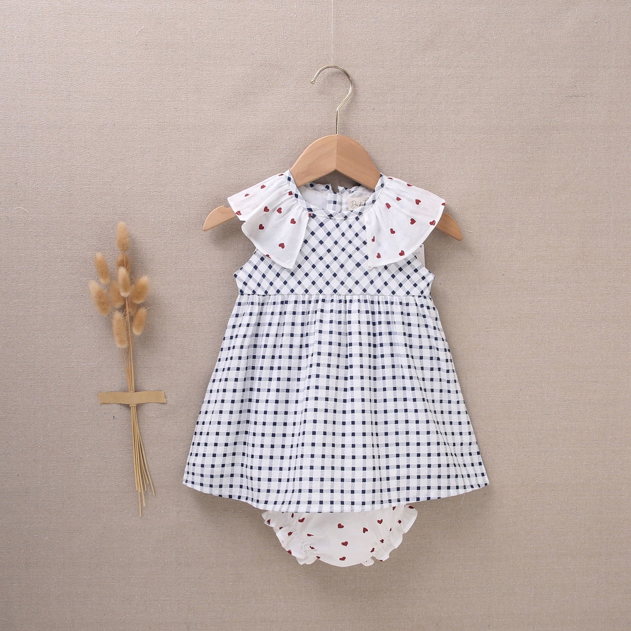 Imagen de Vestido de bebé niña con cubrepañal de cuadros blancos y azul marino con volantes con corazones