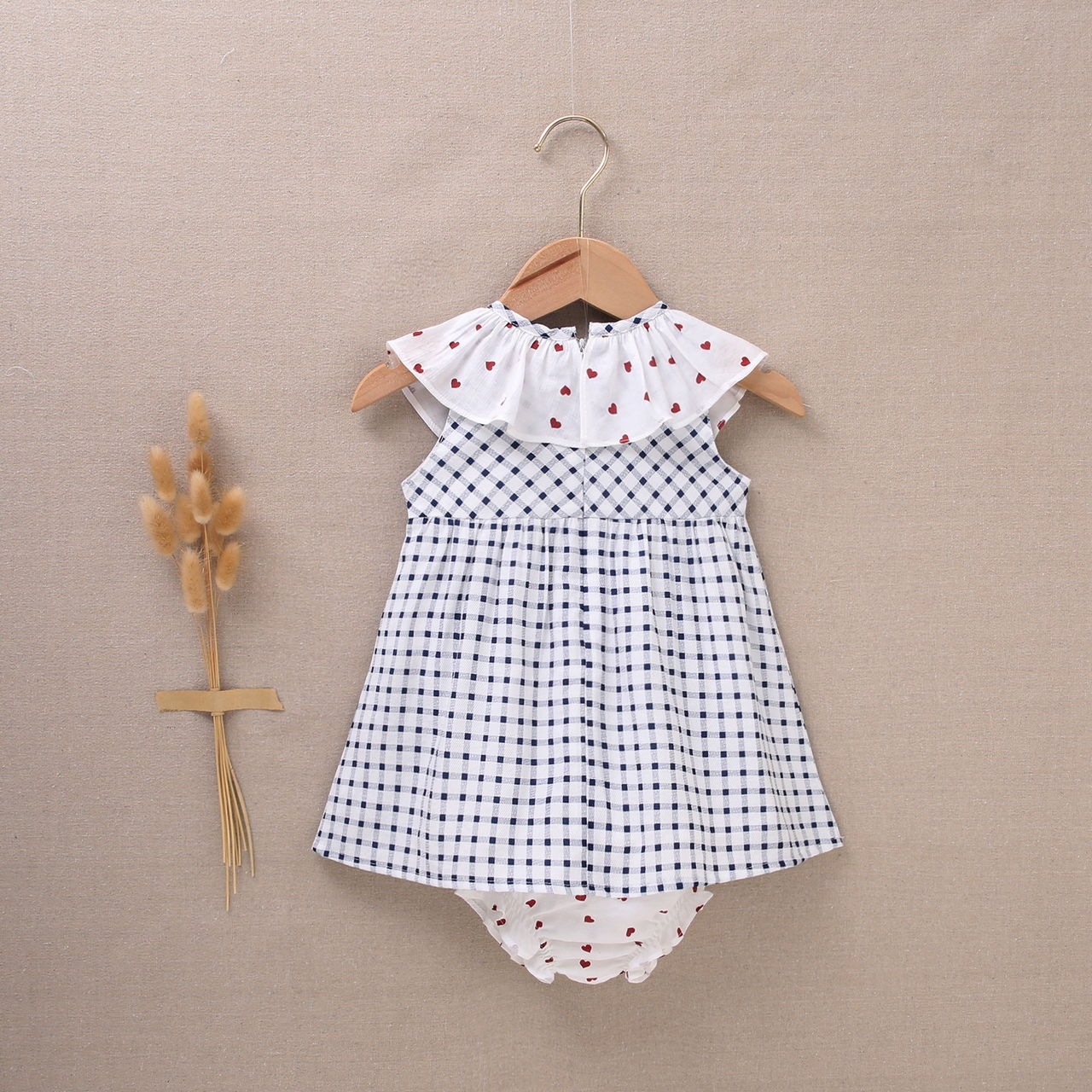 Imagen de Vestido de bebé niña con cubrepañal de cuadros blancos y azul marino con volantes con corazones