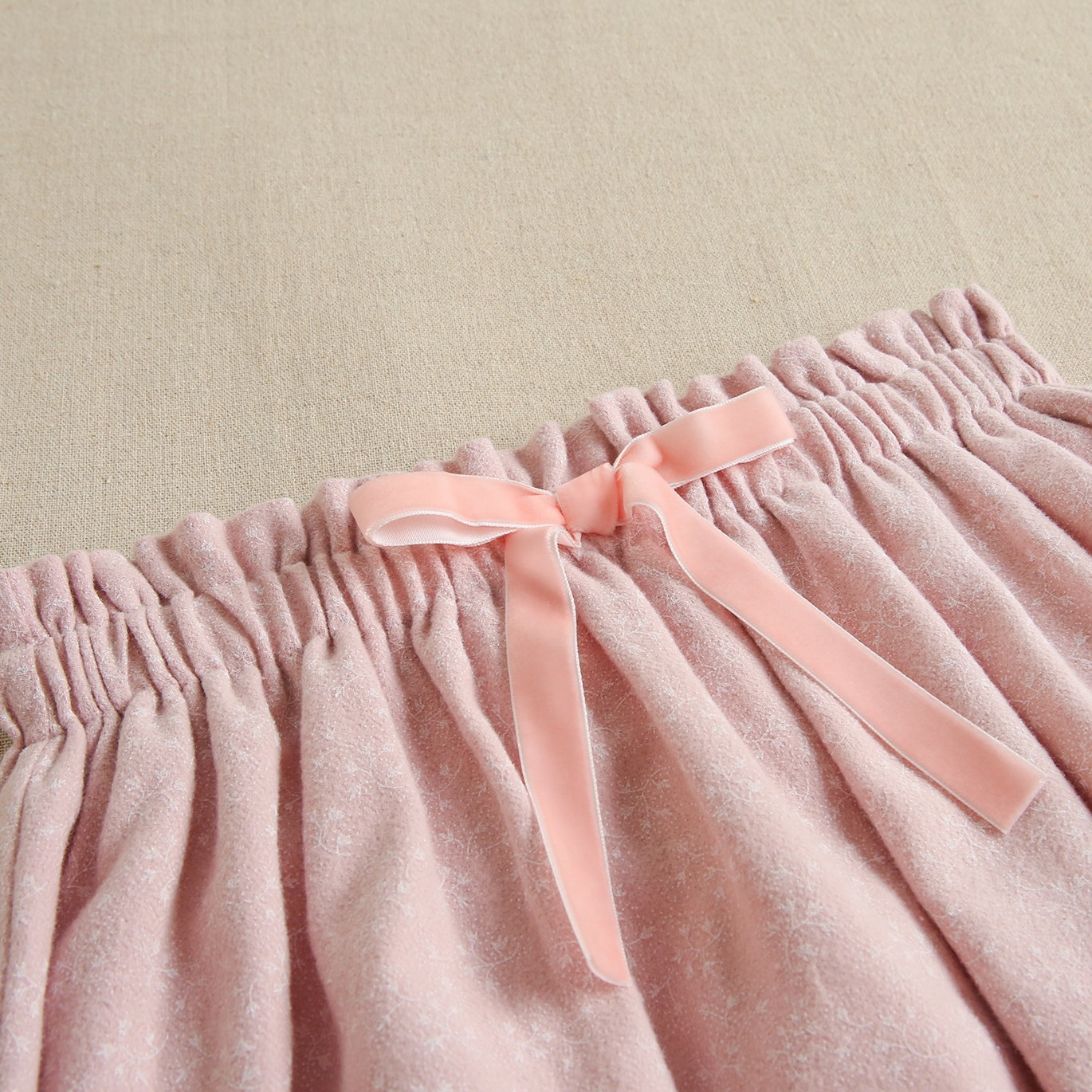 Imagen de Falda de niña con lazo en tejido rosa con estampado de ramitas en blanco
