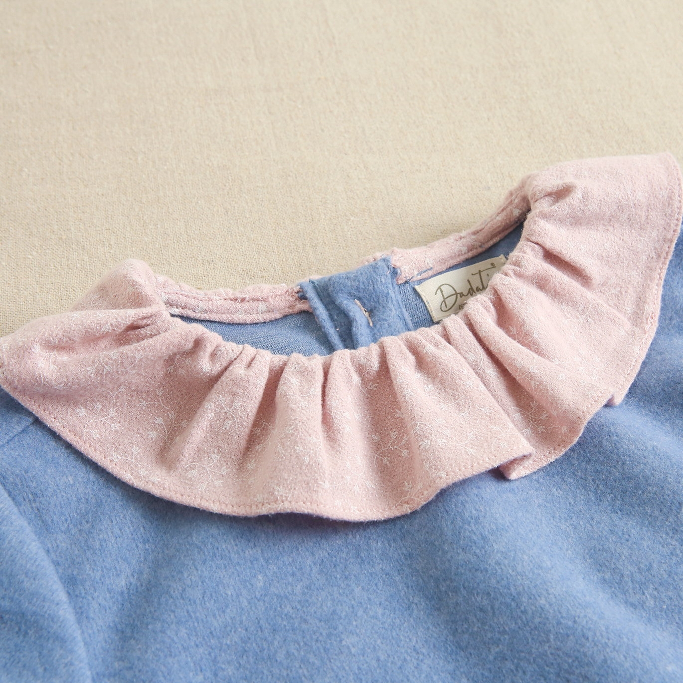 Imagen de Sudadera de niña combinada de tejido azul y rosa con estampado de ramitas en blanco y mangas con elástico
