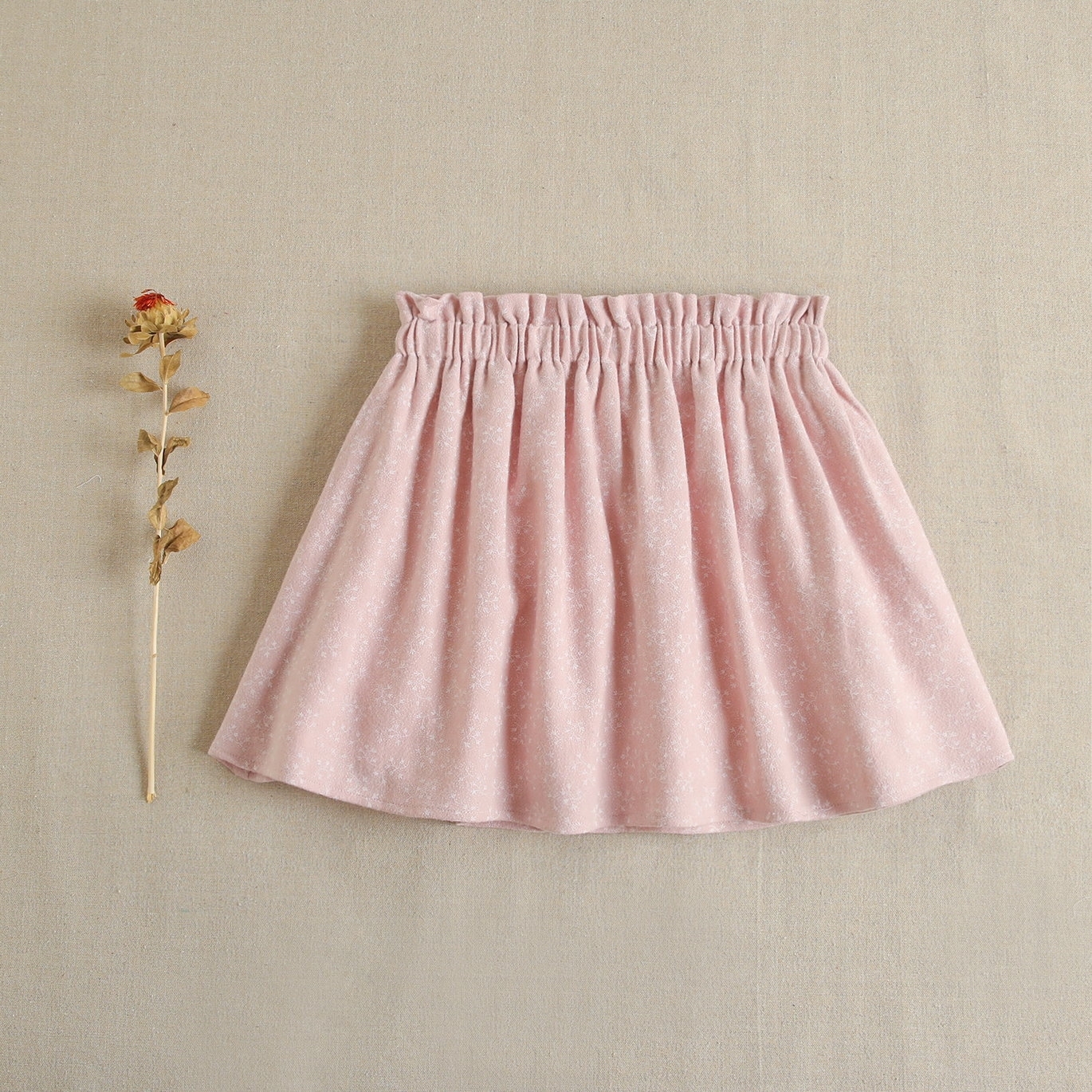 Falda de niña con lazo en tejido rosa con estampado de ramitas en blanco.  Dadati - Moda infantil