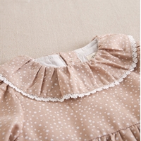 Imagen de Vestido de bebé niña beige tostado con estampado de estrellas blancas y cuello volante