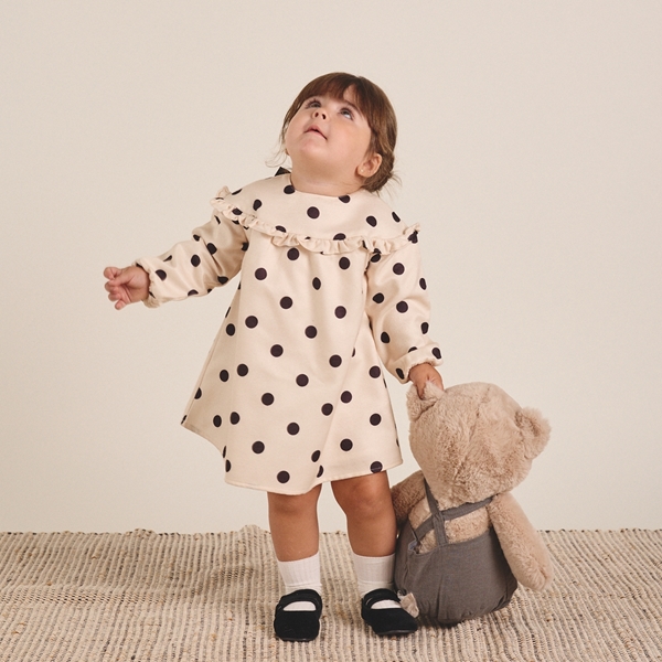 Imagen de Vestido de bebé niña en color crudo con lunares negros y lazo en la espalda